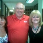Three people smiling in an office hallway.