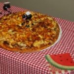 Pizza on checkered tablecloth with decorations.