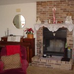 Cozy living room with brick fireplace and red armchair.