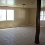 Empty room with tiled floor and large windows.