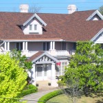 Large house with red roof and trees.
