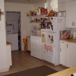 Cozy kitchen with white appliances and decorated refrigerator.