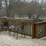 Snowy deck with chairs and trees visible.