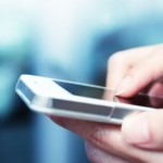 Fingers typing on a smartphone screen.