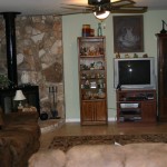 Cozy living room with stone fireplace and wooden furniture.