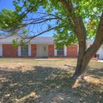 Single-story brick house with a front yard and tree.