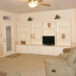 Cozy living room with built-in white shelving and a ceiling fan.