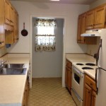Compact kitchen with wooden cabinets and white appliances.