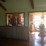 Interior view of a cozy room with wooden accents and a window opening to another sunlit room.