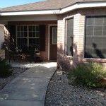 A cozy brick house entrance with a curved walkway and garden plants.