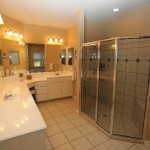 Spacious bathroom with dual sinks and a glass-enclosed shower.