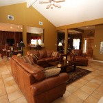 Spacious living room with brown leather sofas and tile flooring.