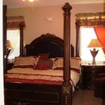 Luxurious four-poster bed with elegant bedding in a warmly lit bedroom.
