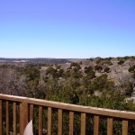 View of a landscape with trees and hills from a wooden deck.