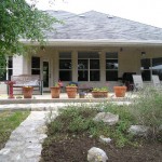 Backyard patio with potted plants and outdoor seating under a covered porch.