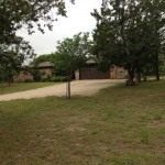A suburban house with a driveway and trees in the yard.