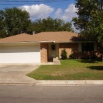 A single-story brick house with a two-car garage and a small front yard.