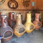 A row of decorative clay chimineas against a rustic wall.
