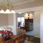 Cozy dining area with wooden table and floral centerpiece near living room.