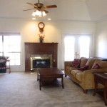 Cozy living room with fireplace, beige carpet, and comfortable furniture.