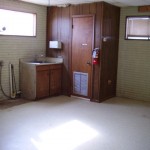 Empty basement with wood paneling and small window.