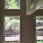 View through windows showing greenery and stone retaining walls outside.